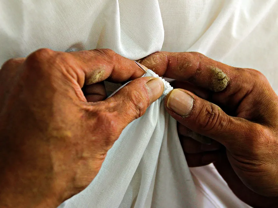Hands stitching white cloth