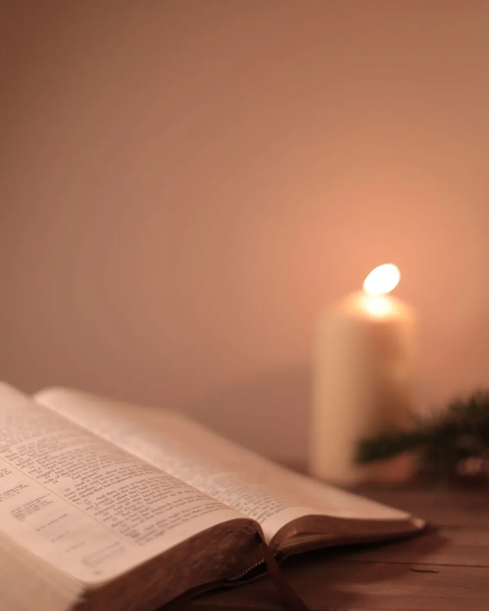 An open Bible beside lit candles